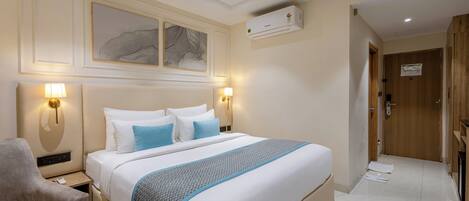 Une chambre d’hôtel équipée d’un lit, de lampes de chevet, d’un bureau, d’une chaise, d’un ventilateur de plafond et d’un appareil de climatisation.
