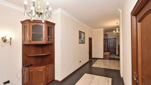 A hallway with a wooden cabinet, a chandelier, and a door at the end. - North ave apartment by Luxe Group HH106 (Yerevan)