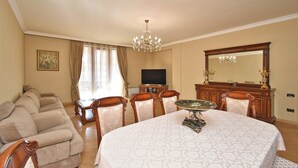 A hotel room with a large bed, a dining table, a television, a chandelier, and a large mirror. - North ave apartment by Luxe Group HH106 (Yerevan)