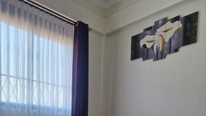 Une chambre à coucher avec un lit, un vase rempli de fleurs jaunes et un tableau accroché au mur.