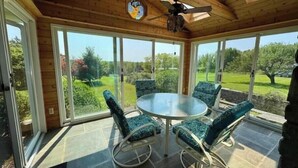 A sunroom with a glass door, a ceiling fan, and a round table with chairs. - Ahrens Rd Ranch (Parksville)