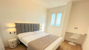 Un dormitorio con cama, mesitas de noche, ventana y una silla.