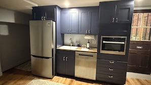 A modern kitchen with dark cabinets, a stainless steel refrigerator, a sink, and an oven. - 1BR Bloomingdale Retreat with Private Entry. Walkable & Quiet Neighborhood.   (Washington)