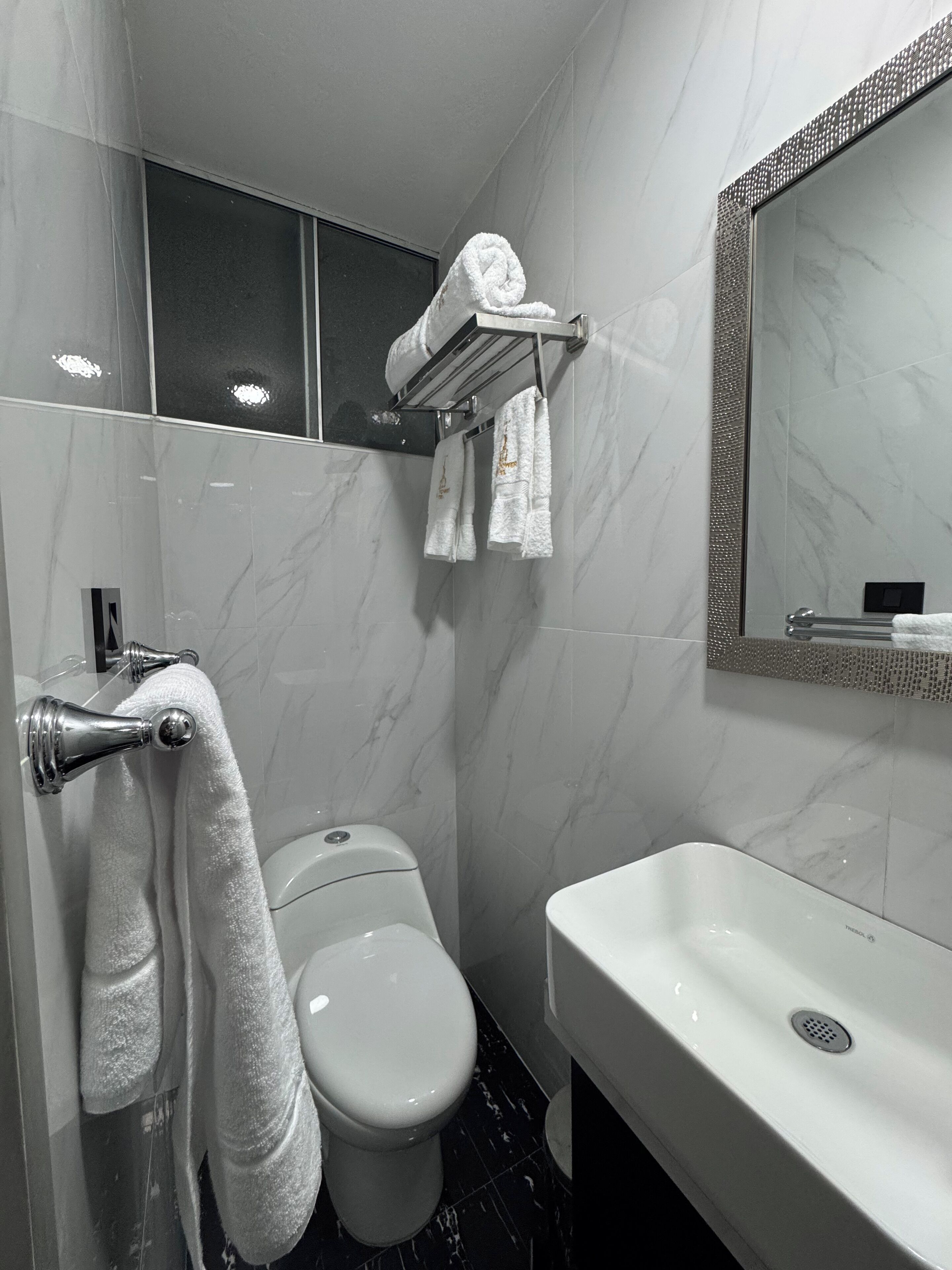 Un baño moderno con inodoro, lavamanos y perchero para toallas.