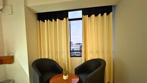 A room with two black armchairs, a small wooden table, and a potted plant. - City Tower Hotel (Santiago de Surco)
