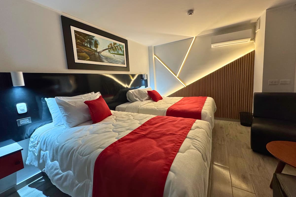 Une chambre d’hôtel moderne avec deux lits, un tableau, un bureau et un canapé.
