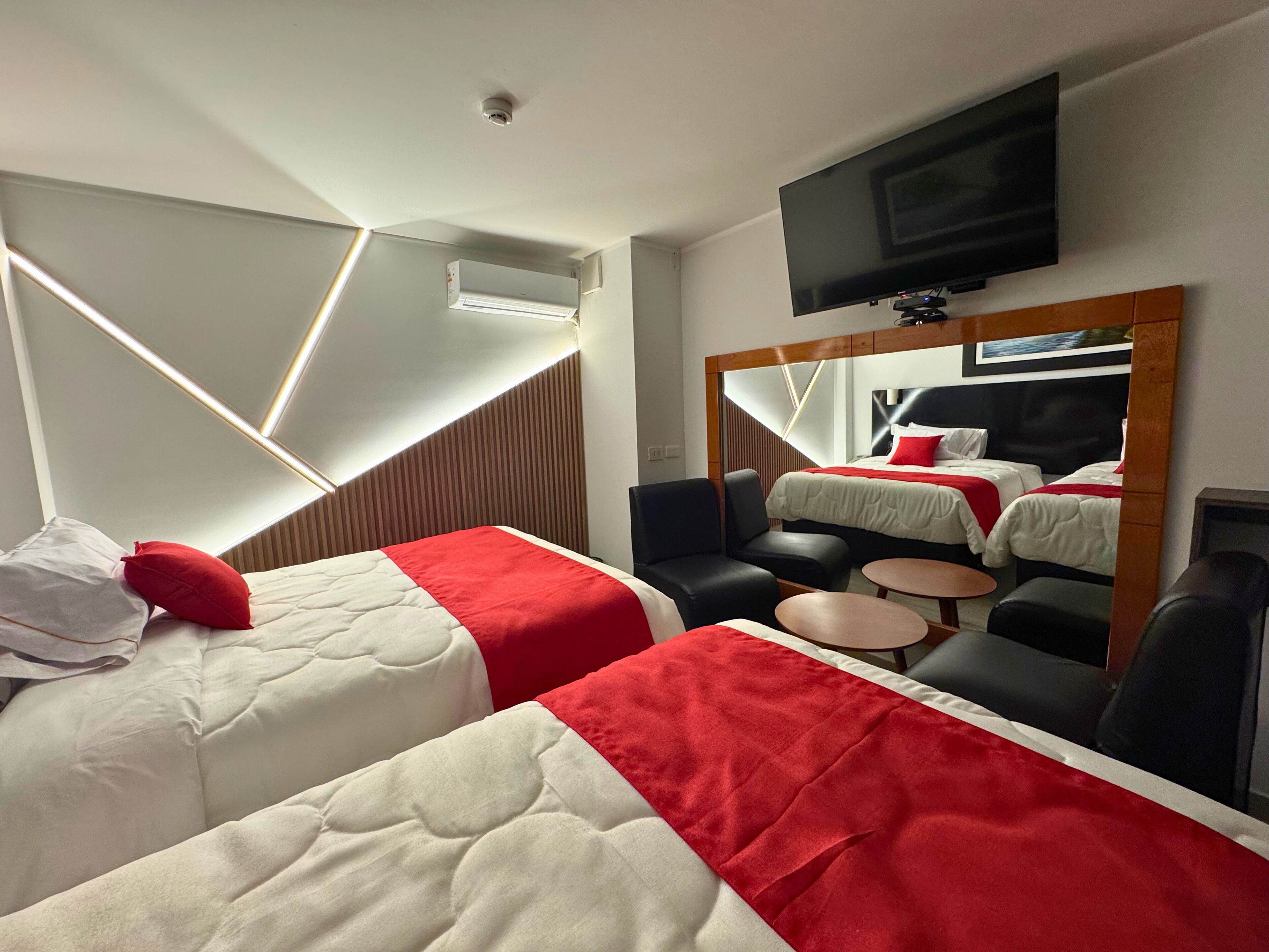 Una habitación de hotel con dos camas, televisión, una mesita y zona de estar.