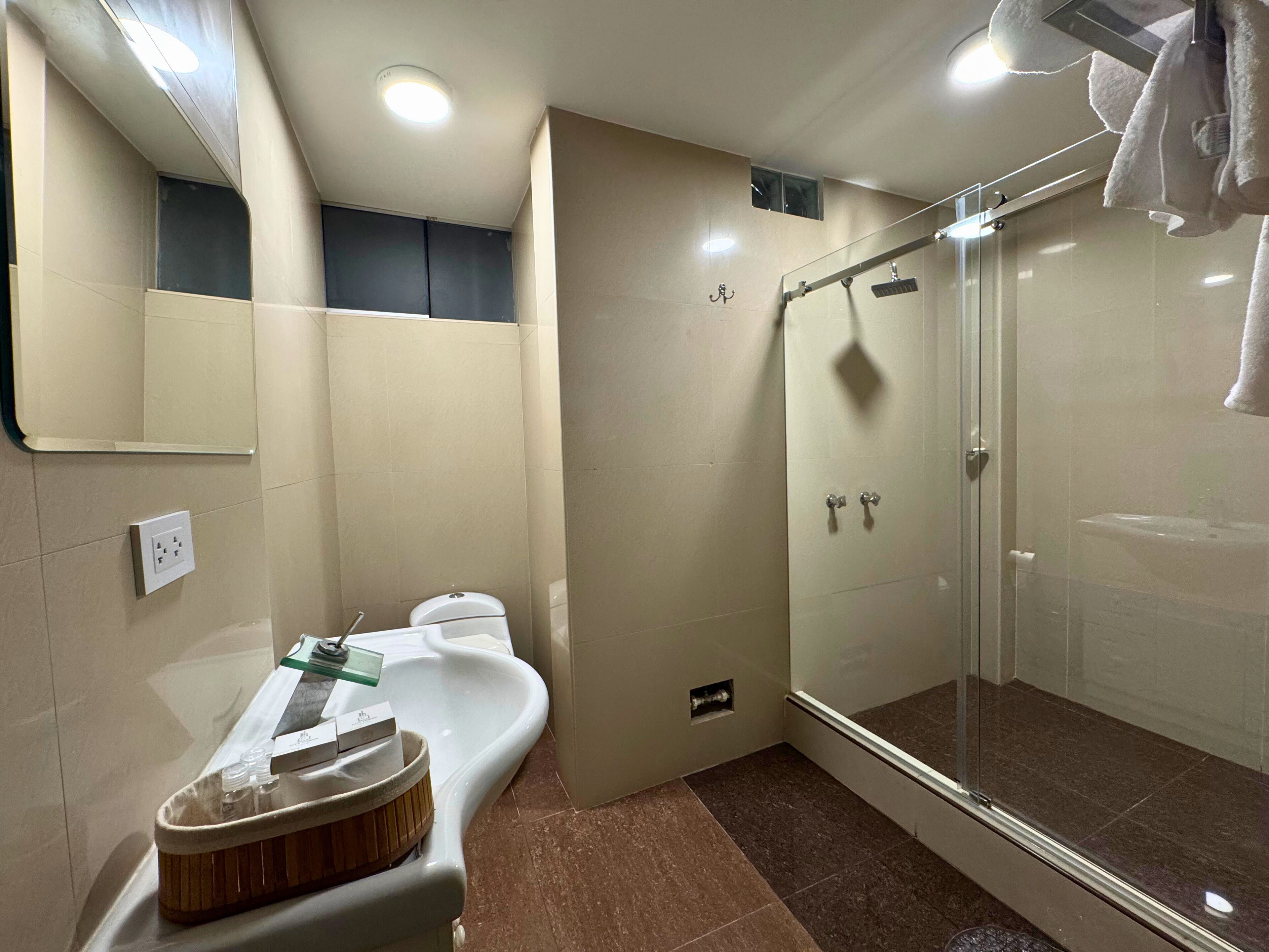 A bathroom with a sink, mirror, toilet, shower, and towel rack.
