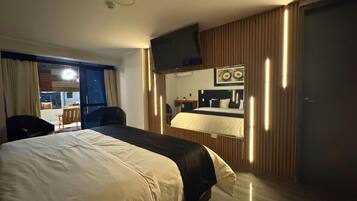 Una habitación de hotel con una cama grande, un escritorio, una silla, un televisor y una ventana con cortinas.