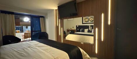Una habitación de hotel con una cama grande, un escritorio, una silla, un televisor y una ventana con cortinas.