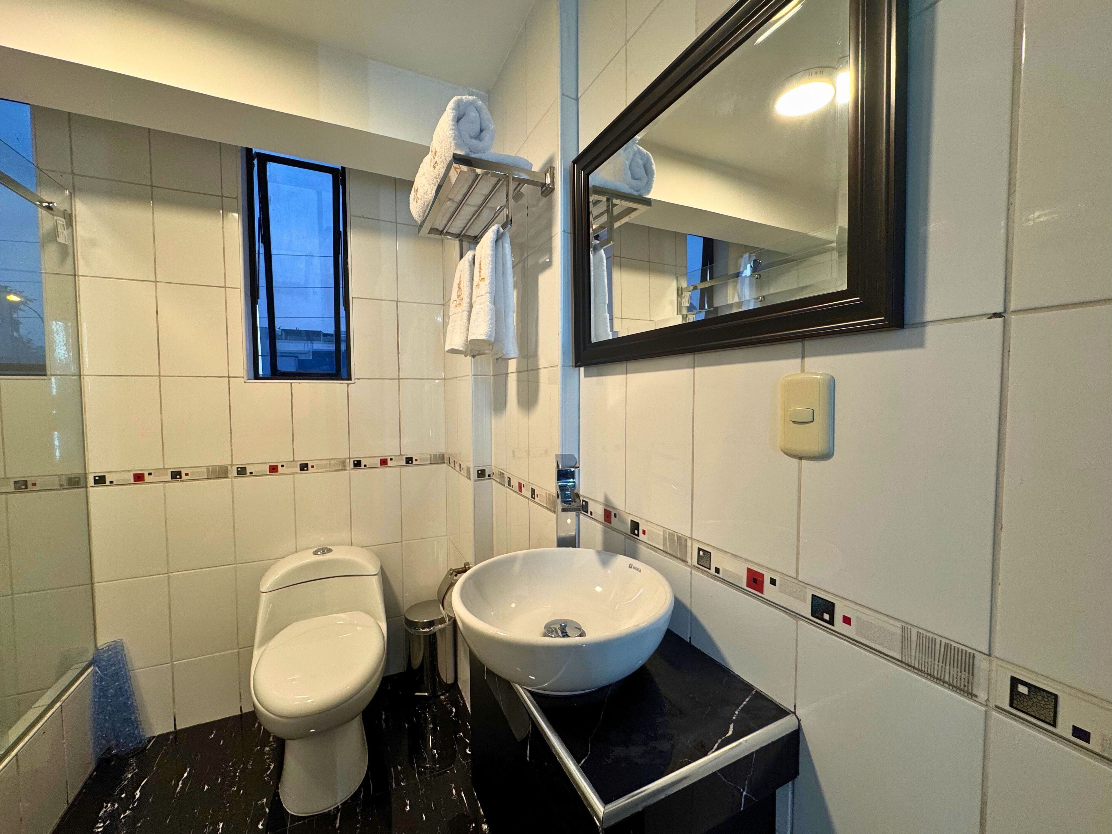 A modern bathroom with a toilet, sink, and a towel rack.