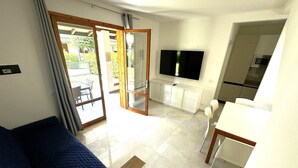 Una stanza con un letto, una TV, un tavolo da pranzo e un angolo cottura.