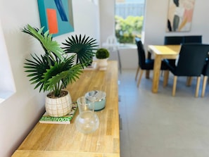 A wooden table with a potted plant, a glass vase, and a book. - Seascape Beach House Retreat (Halls Head)