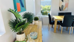 Une table en bois sur laquelle sont posés un pot de fleurs, une carafe en verre et un livre intitulé « Roo Minneple ».