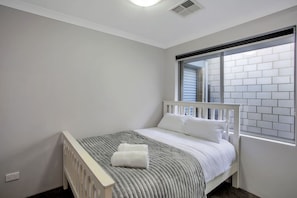 A bedroom with a single bed, a window with blinds, and a white ceiling vent. - Seascape Beach House Retreat (Halls Head)