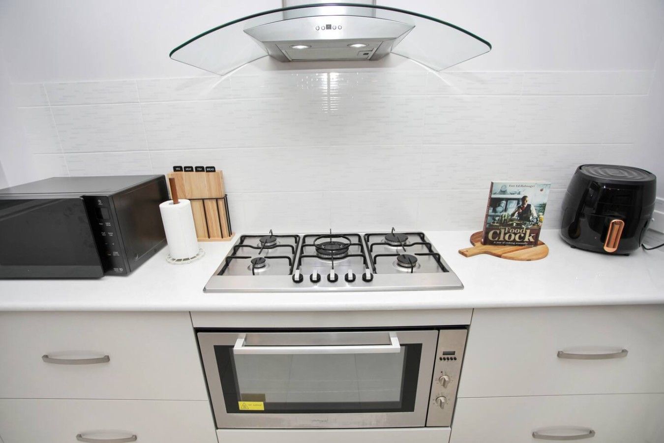 A kitchen with a gas stove, oven, microwave, and a coffee maker on the counter.