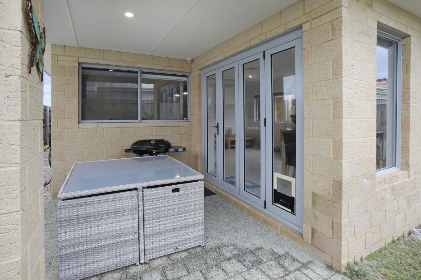 A patio area with a grill, a wicker table, and a sliding glass door.