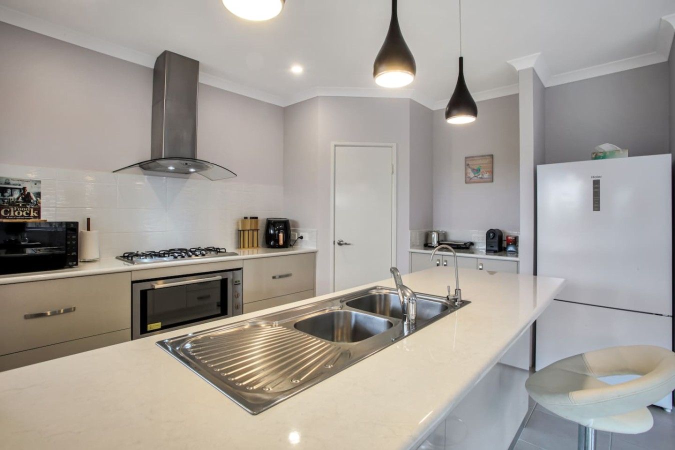 A modern kitchen with stainless steel appliances, a double sink, and pendant lighting.