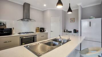 A modern kitchen with stainless steel appliances, a double sink, and pendant lighting.