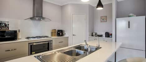 Een moderne keuken met roestvrijstalen apparatuur, een dubbele spoelbak en hanglampen.