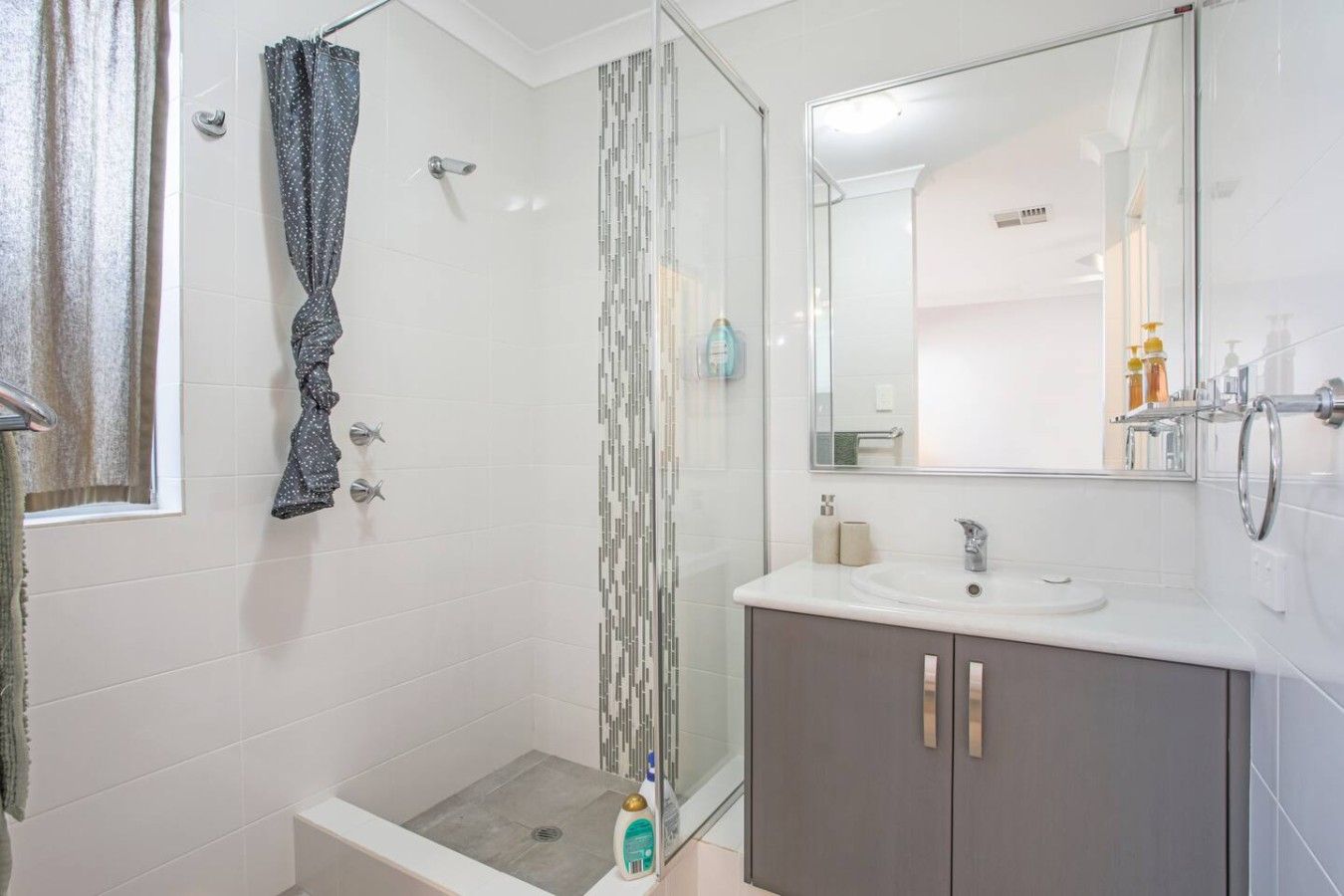 A bathroom with a shower, a sink, and a mirror.