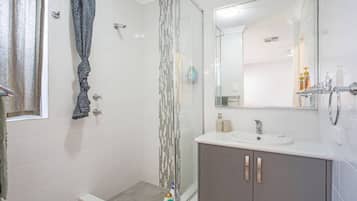 A bathroom with a shower, a sink, and a mirror.