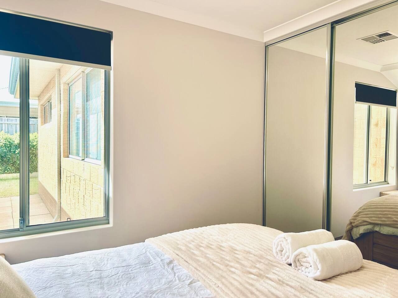Een hotelkamer met een groot raam, een bed met witte lakens en een spiegel.