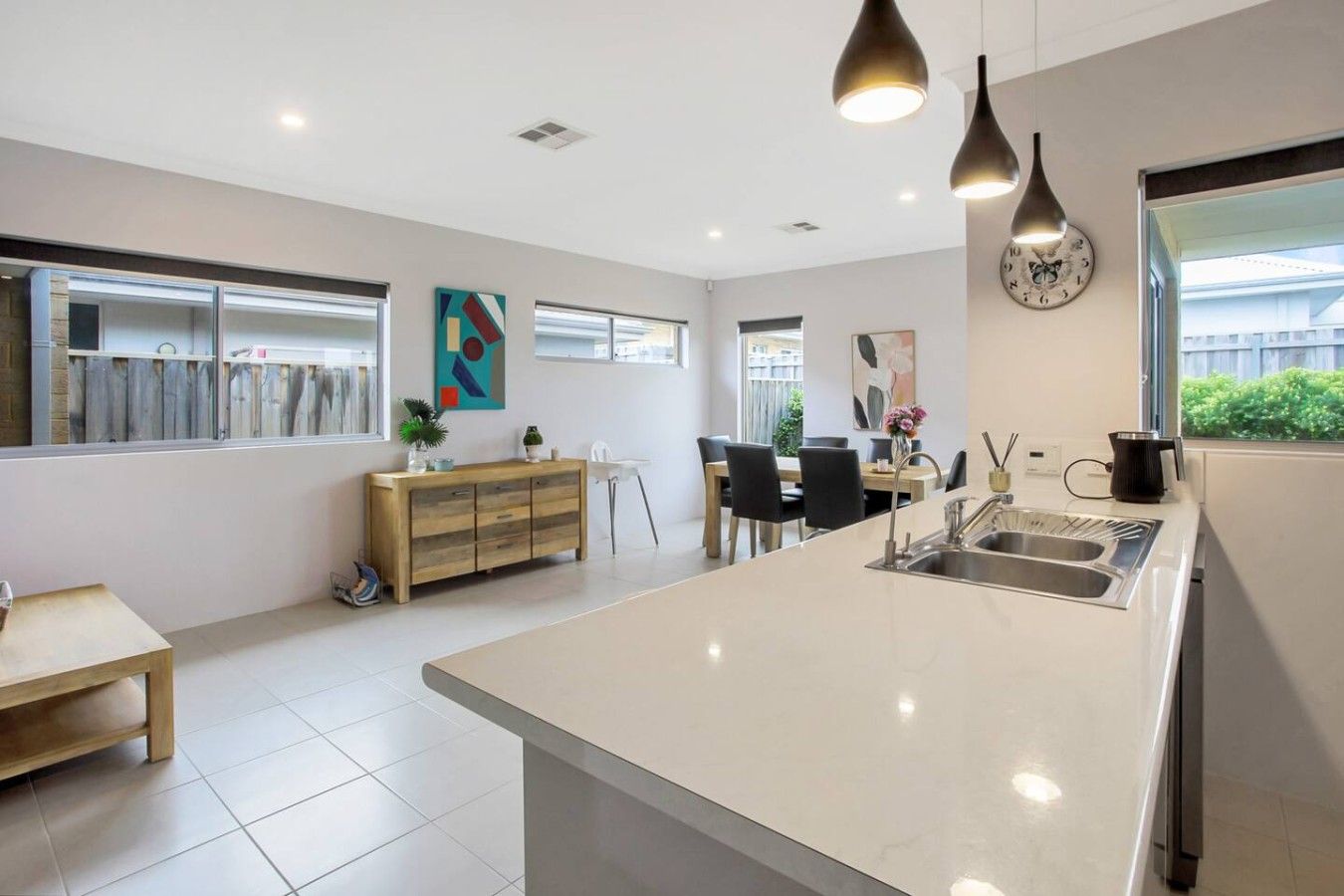 A modern kitchen with a large island, a dining area with chairs, and a view of the outside.