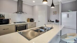 Une cuisine moderne dotée d’un évier en acier inoxydable, d’une cuisinière à gaz et d’un four encastré.