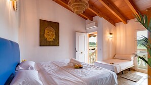 Een kamer met twee bedden, een Boeddhabeeld, een houten plafond en uitzicht door een geopende deur.