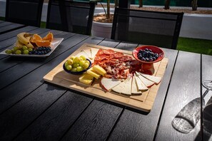 A wooden table with a charcuterie board, fruits, and a bowl of blueberries. - villa salvaje beach (PALMA DE MALLORCA)