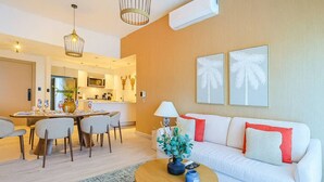 Ein modernes Wohnzimmer mit einem weißen Sofa, einem runden Couchtisch und einem Essbereich, der für vier Personen gedeckt ist.