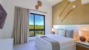 Ein modernes Hotelzimmer mit einem großen Bett, Blick auf Grün durch das Fenster und einem an der Wand befestigten Holzschaufel.