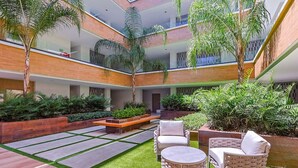 Ein mehrgeschossiges Atrium mit einem zentralen Innenhof, Sitzmöglichkeiten im Freien und üppiger Bepflanzung.