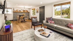 A modern living room with a sofa, coffee table, and a dining area with chairs and a table. - The Green Gem (Crestone)