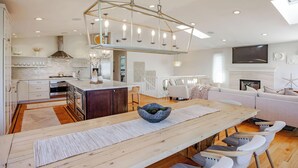 Une cuisine moderne avec des meubles blancs, un îlot central et un luminaire suspendu.