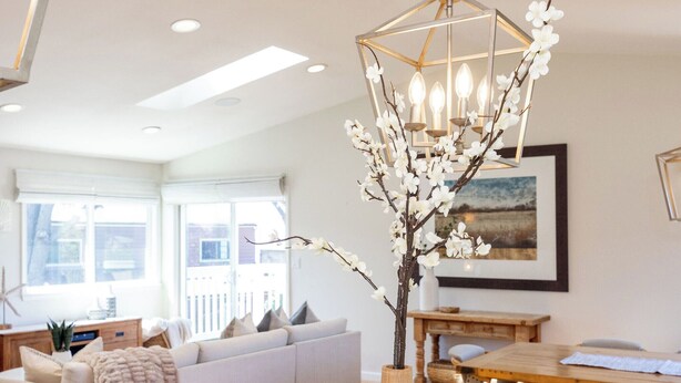 Un salon moderne avec une table à manger en bois, un canapé et un luminaire suspendu orné de branches.
