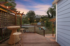 A wooden deck with a pergola, outdoor seating, and string lights.