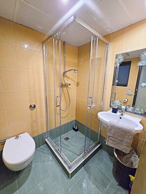 Ein Badezimmer mit Duschkabine, Waschbecken und Toilette.