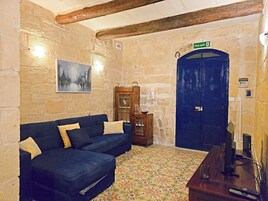 A room with a blue sofa, a wooden cabinet, a patterned floor, a blue door, and a painting on the wall.