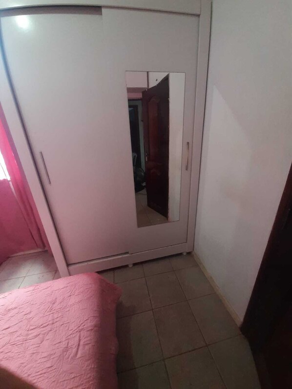 A bedroom with a bed, a wardrobe, and a mirror.