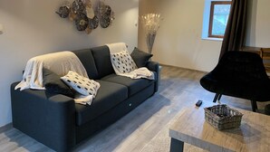 En moderne stue med en mørkegrå sofa, dekorativ vægkunst og træloft.