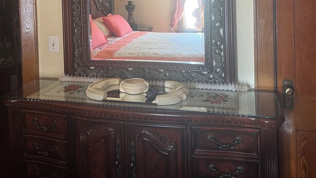 Une commode en bois avec un miroir, des tiroirs et une table ornée d’une bordure en dentelle.