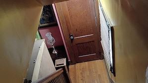 Un escalier en bois, muni d’une rampe, mène à une porte.