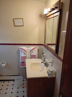 Ein Badezimmer mit einem weißen Waschbecken, einem Spiegel und zwei Handtüchern mit roten Streifen.