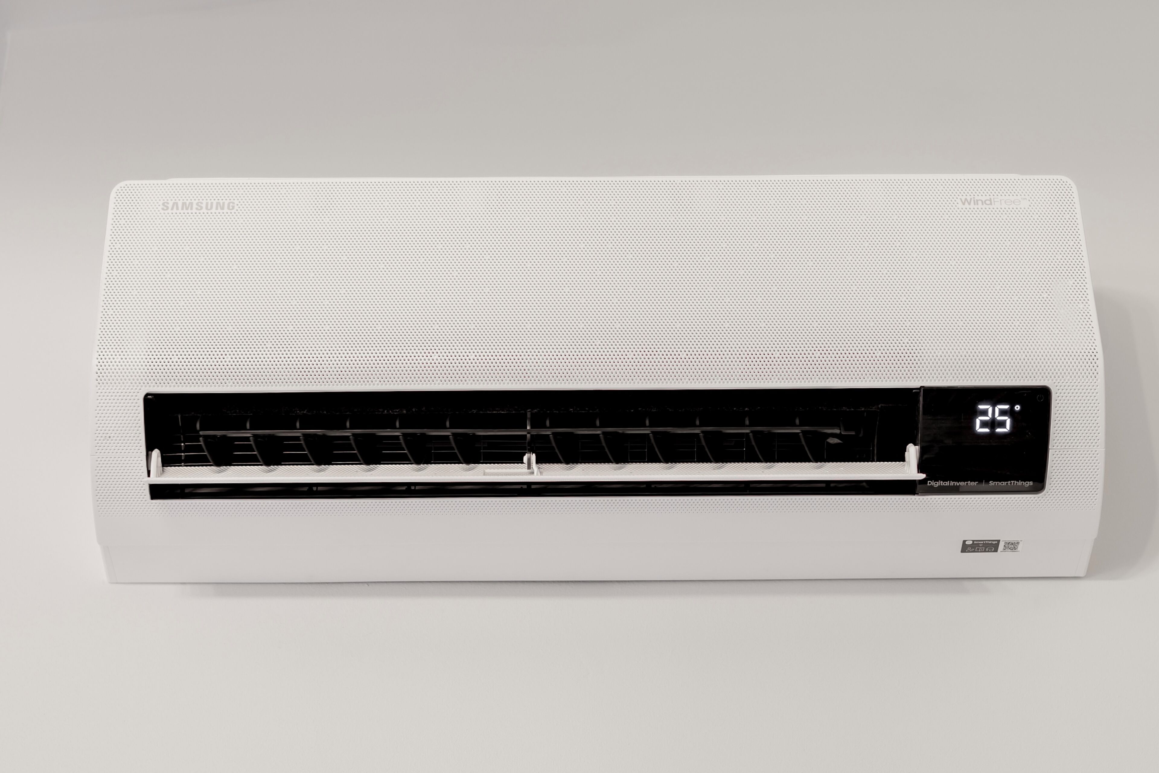 Eine weiße Klimaanlage mit digitaler Anzeige, die 25 Grad Celsius zeigt.