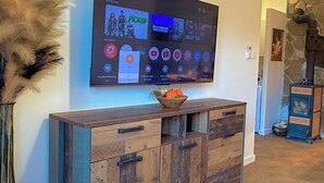 A wooden cabinet with multiple drawers and a television mounted above it. - Residence S5 - Comfort Living Apartment  (Prešov)