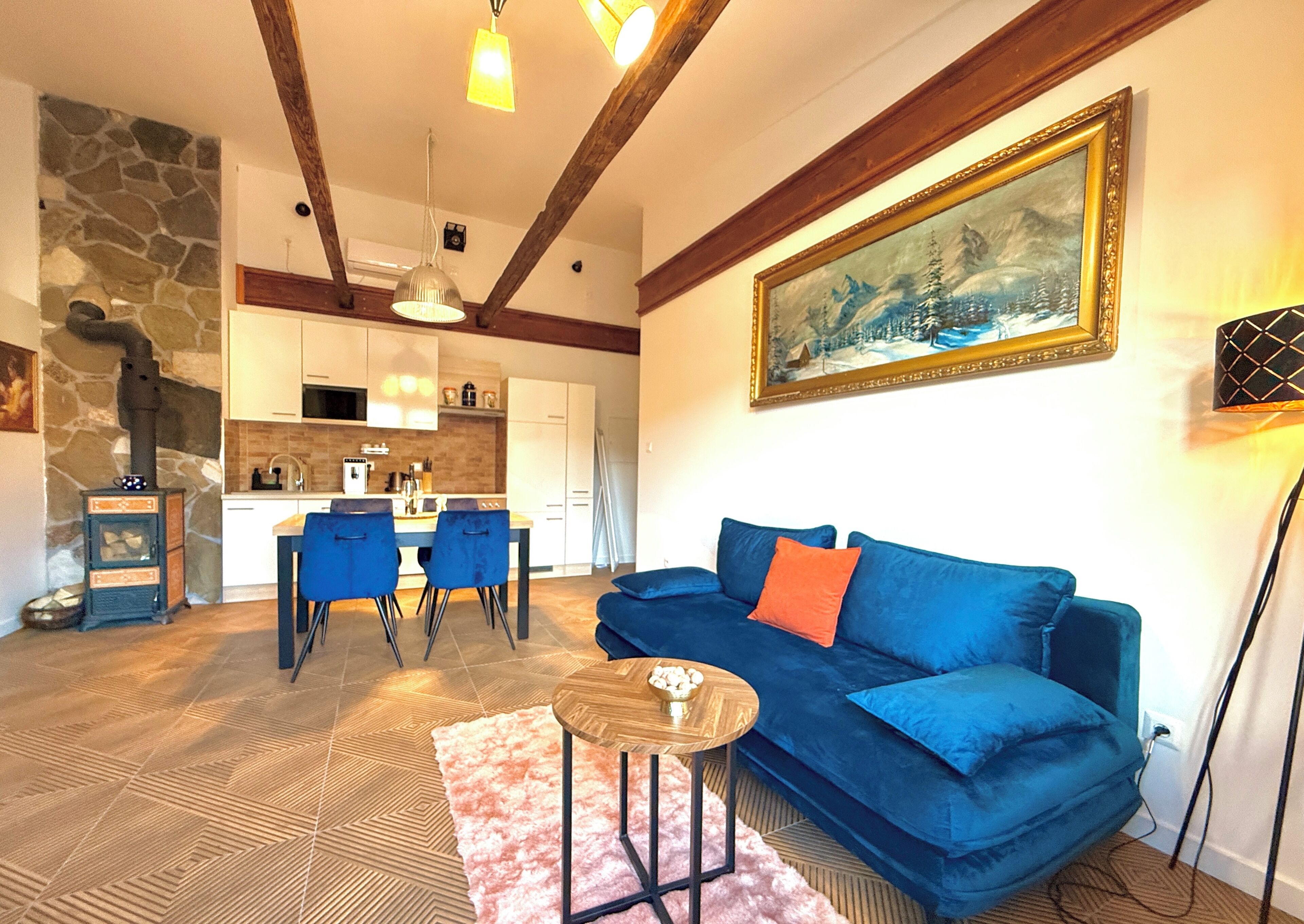 A cozy living room with a blue sofa, a coffee table, and a stone fireplace.