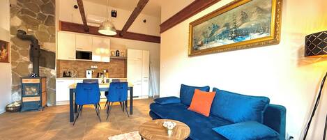 Un salón acogedor con un sofá azul, una mesa de centro y una chimenea de piedra.