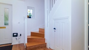 Una escalera de madera con peldaños que conducen a un rellano con un ventanal pequeño.